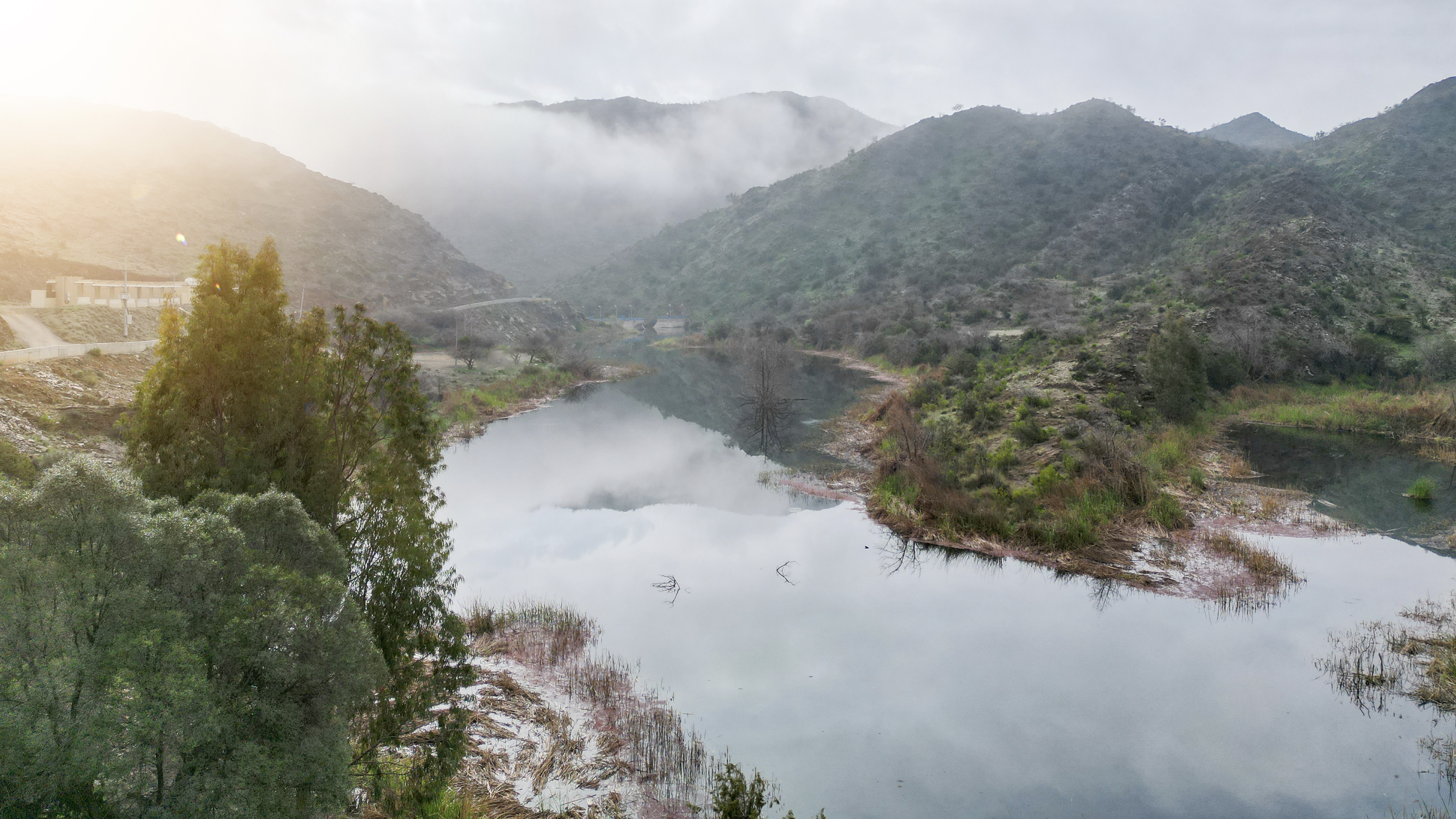 a river with trees and mountains in the background